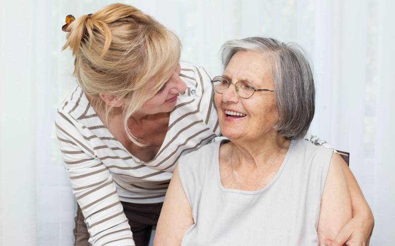 A woman is talking to an older woman in a chair.