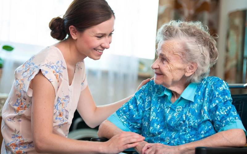 A woman talking to an elderly woman in a wheelchair.