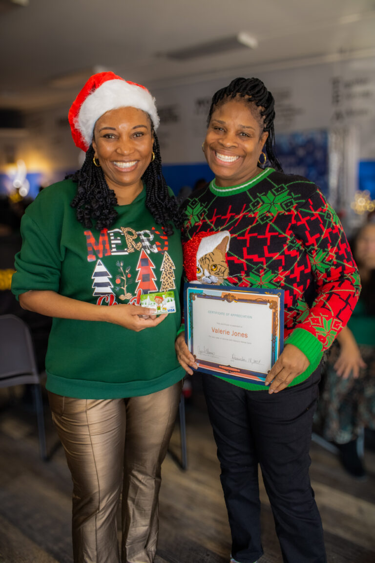 Two women celebrating with awards and festive outfits.