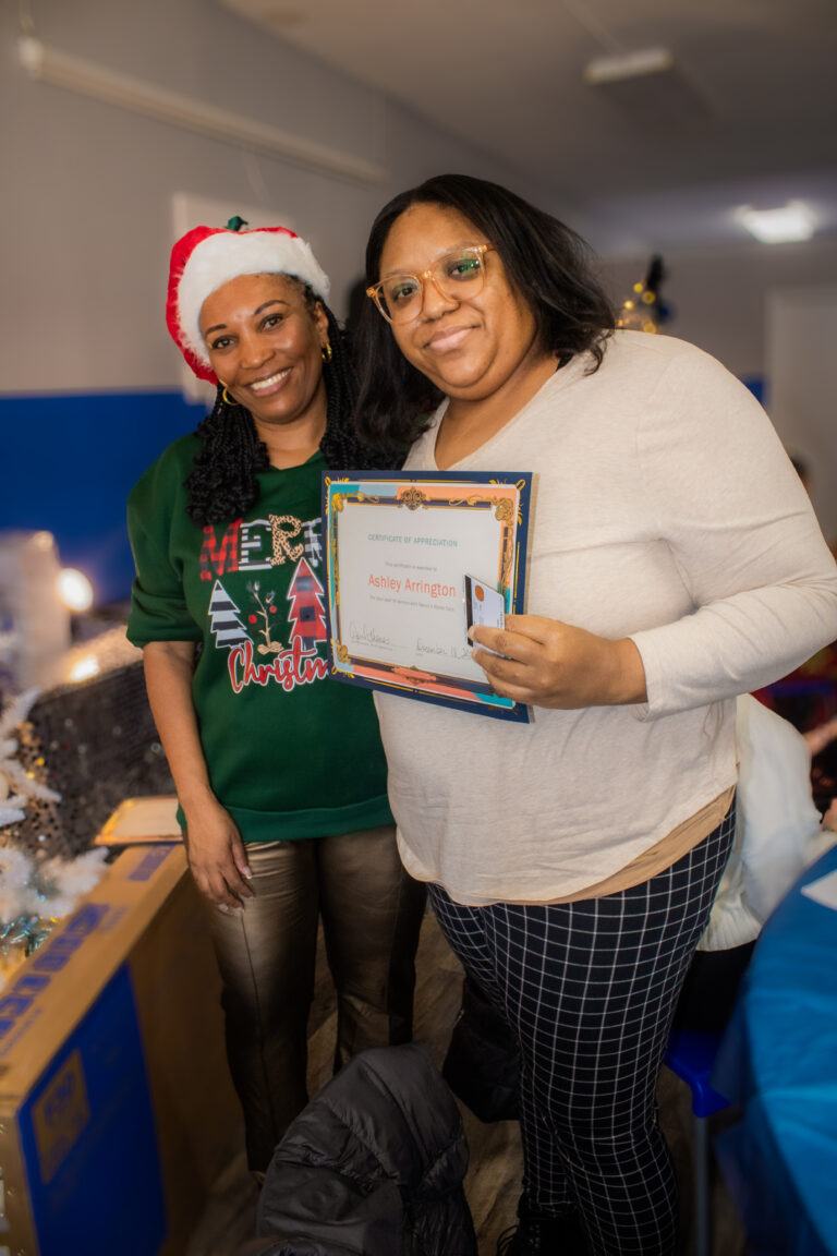 Two women celebrate with a certificate.