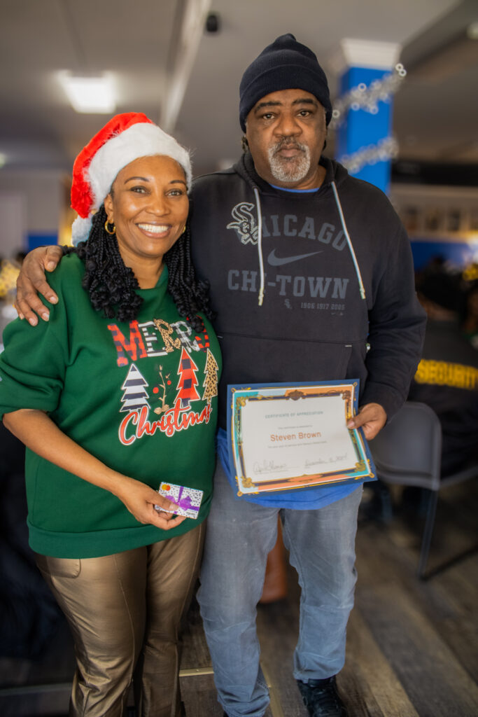 Smiling couple with Christmas certificate of appreciation.